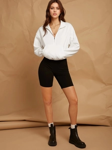 White quarter-zip sweatshirt paired with black cycling shorts and stylish chunky boots