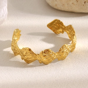 Detailed view of golden stainless steel open bangle with embossed strawberry pattern