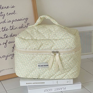 Close-up of quilted cream polka dot cosmetic bag with dual zippers and fabric handle