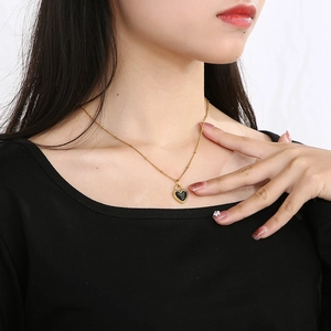Close-up of heart pendant necklace with black center and gold trim on female model