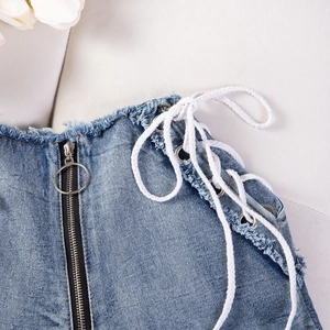 Dettaglio degli shorts in denim a vita alta con bordi sfrangiati e lacci laterali bianchi