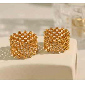 Detailed view of gold plated honeycomb rings with Czech crystals on beige ceramic stand