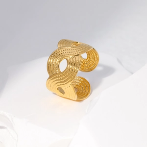 Macro detail of gold-plated open ring featuring intricate hollow wave texture on stone