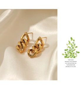 Nahaufnahme goldener grober Kettenohrringe auf elegantem weißem Seidenhintergrund