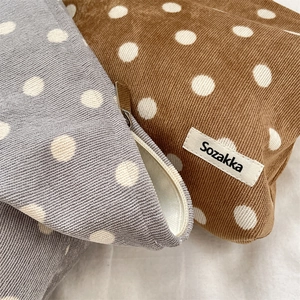 Close-up of polka dot corduroy pouches in grey and brown with metal zipper detail