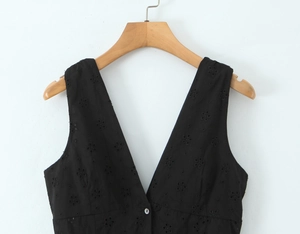 Détail d'une robe noire sans manches à col en V avec broderie florale et bouton central