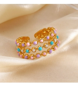 Detail of gold triple-layered open ring with colorful resin beads on silk background