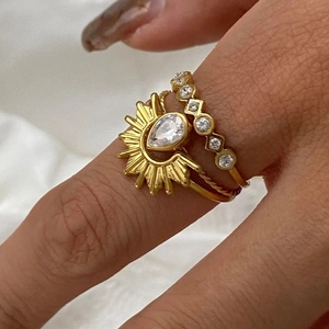 Three-piece stackable gold ring set with sunburst design and teardrop cubic zirconia