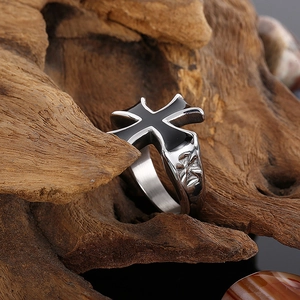 Macro shot of punk stainless steel cross ring with black oil drip on textured wood