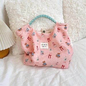 Detail of pink embossed canvas bag with rabbit prints and blue braided rope handles
