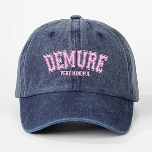 Detail der dunkelblauen gewaschenen Jeans-Basecap mit rosa DEMURE-Stickerei