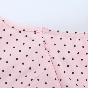 Close-up of invisible zipper and black polka dots on pink v-neck dress fabric