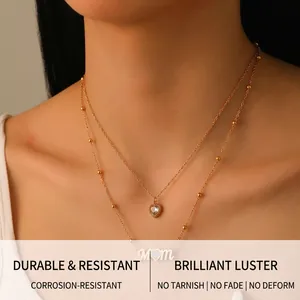 Close-up of a layered gold necklace featuring a diamond heart and MOM letter pendant