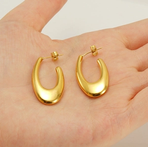 Detailed view of hollow gold U-shape earrings held in hand for size comparison