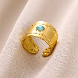 Close-up of bohemian wide gold ring with blue semi-precious stone on linen fabric