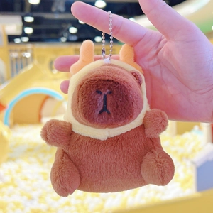 Macro detail of plush capybara keychain wearing a yellow reindeer hood with metal chain