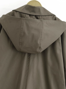 Detail of olive green hooded coat back seam and twill fabric texture on wooden hanger