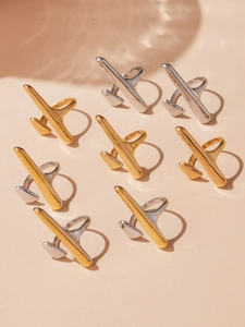 Detailed view of airplane-shaped gold and silver rings on a textured beige background