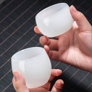 Close-up of white macaron glass wine goblets with a smooth texture held by hands