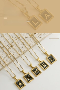 Detailed macro view of rectangle 18K gold plated letter pendant with black oil drop