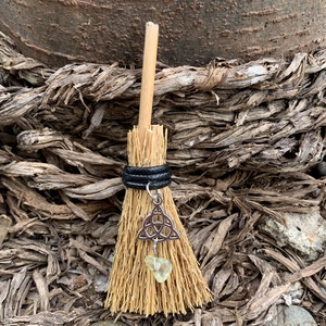 Macro view of a miniature witch broom pendant with triquetra charm and yellow gemstone