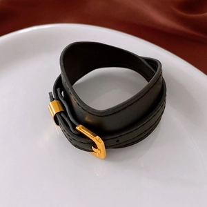 Detail of black faux leather double-wrap bracelet with golden buckle on satin