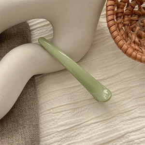 Detail of light green seamless hair clip with glossy finish and metal spring mechanism