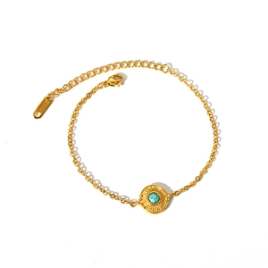 Bracelet vintage en acier inoxydable doré avec pendentif soleil turquoise sur fond blanc