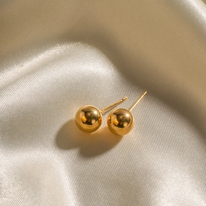 Classic 18K gold plated stainless steel ball stud earrings on champagne silk background