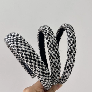 Macro detail of houndstooth plaid headbands showing textured fabric and handmade label