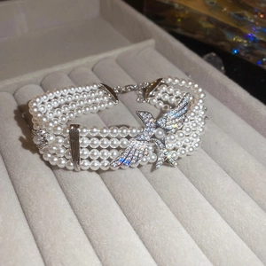 Détail macro du bracelet perles multi-rangs avec un motif d'oiseau serti de cristaux brillants