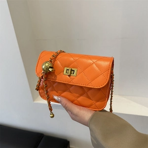 Close-up of orange quilted crossbody bag featuring gold chain and spherical metal clasp