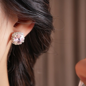 Detailed view of pink gemstone flower earrings with sparkling diamond halo on model