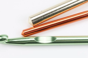Macro detail of high-quality aluminum crochet hooks in gold, orange, and light green finish