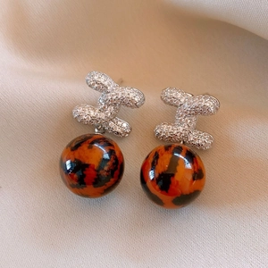 Close-up of leopard print drop earrings with sparkling pavé crystal chain links