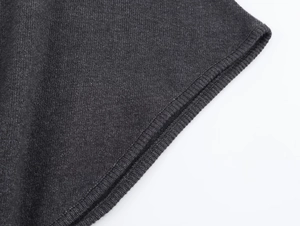Détail du tissu en maille gris foncé montrant la couture surjetée et la texture raffinée