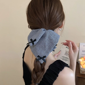 Detail of checkered bow hair scrunchie shown on a ponytail in a lifestyle setting