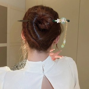 Detail of vintage style hair stick with pearl flowers and green jade disc in a hair bun