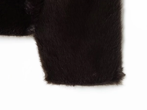 Détail rapproché des poignets en fourrure synthétique noire sur veste réversible