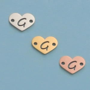 Macro detail of heart-shaped metal connectors with hollow letter G in three colors