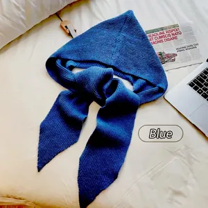 Detailed view of a soft blue knitted hooded scarf flat lay on a white bed sheet