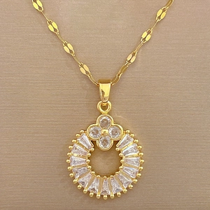 Macro detail of gold clover pendant with cubic zirconia inlay on silk fabric