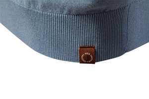 Macro shot of blue ribbed knit hem featuring a brown decorative brand tag for polo shirts