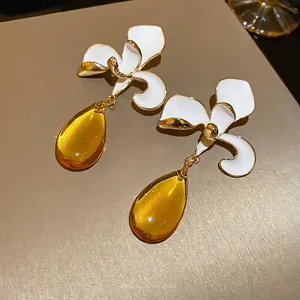 Floral stud earrings with white enamel orchid petals and amber teardrop pendants