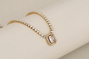 Close-up of golden tennis chain with a rectangle crystal pendant and micro pave cubic zirconia