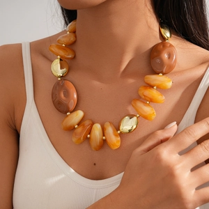 Detailed close-up of chunky amber and gold geometric acrylic beads on a layered necklace
