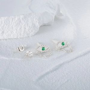 Detailed view of S925 sterling silver evil eye studs with green gems and chain fringe