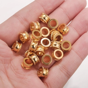 Macro shot of gold stainless steel textured spacer beads held in palm for DIY jewelry