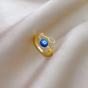 Detail of 18K gold-plated leaf ring with blue evil eye zircon on silk fabric