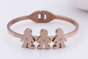 Close-up of rose gold bracelet with three small boys figures and sparkling crystals